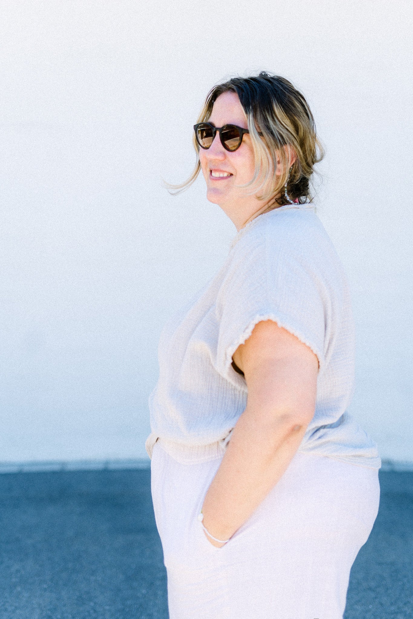 Jennifer wears light cotton blouse and pants, sunglasses and a Chubby Candy bracelet. She smiles into the camera.